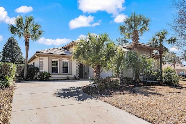 mediterranean / spanish house with a tile roof, driveway, and stucco siding