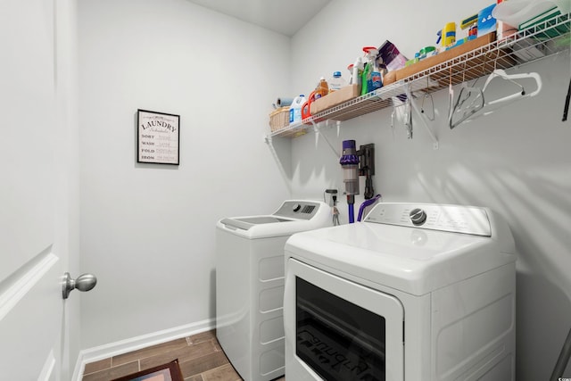 laundry room featuring laundry area, wood tiled floor, baseboards, and separate washer and dryer