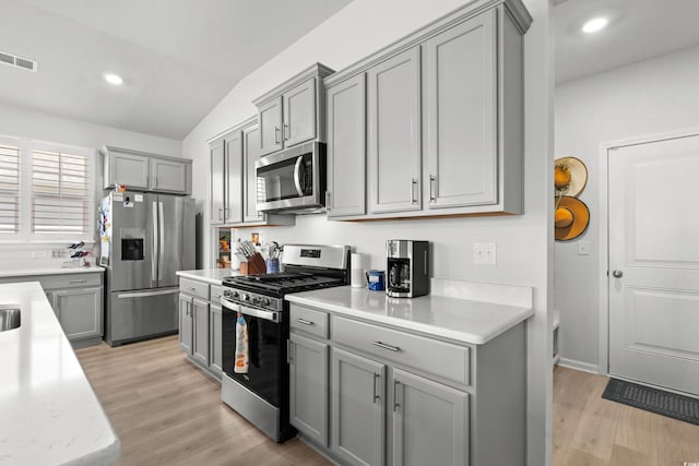 kitchen featuring stainless steel appliances, light countertops, gray cabinets, and visible vents