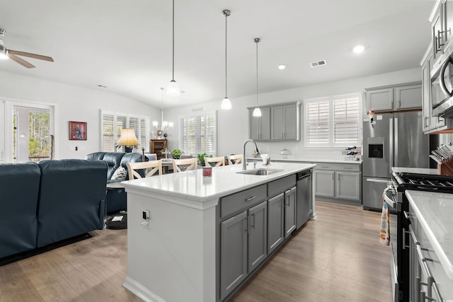 kitchen with appliances with stainless steel finishes, open floor plan, a sink, and gray cabinetry