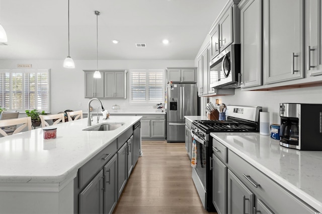 kitchen featuring appliances with stainless steel finishes, light wood-style floors, gray cabinets, and a sink