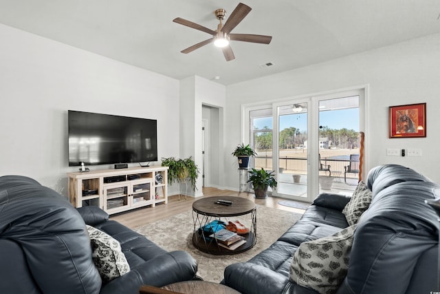 living room with a ceiling fan, visible vents, baseboards, and wood finished floors