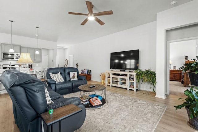 living area with ceiling fan, light wood-style flooring, and baseboards