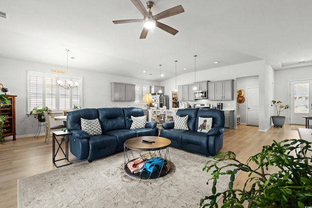 living room featuring light wood finished floors, recessed lighting, visible vents, baseboards, and ceiling fan with notable chandelier