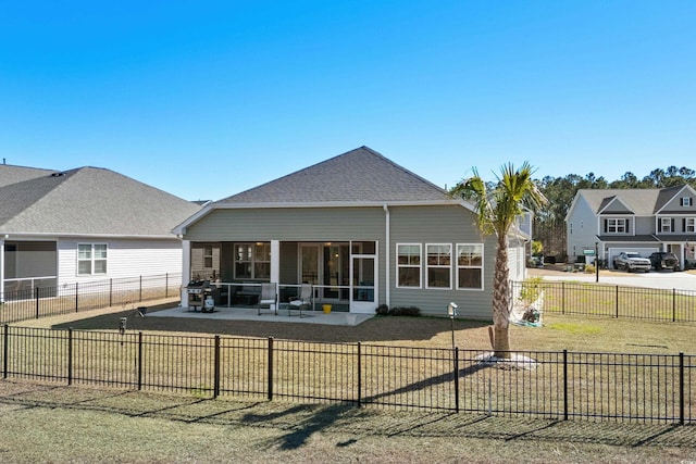 rear view of house with a patio, a fenced backyard, a shingled roof, a sunroom, and a yard