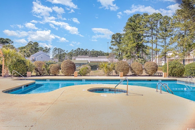 pool with a patio area and a hot tub