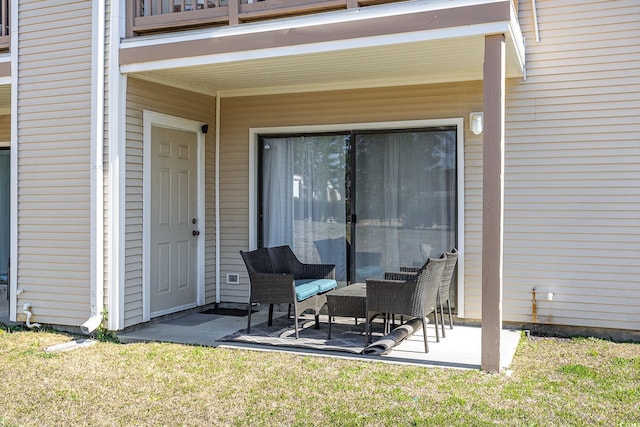 view of exterior entry with a balcony and a lawn