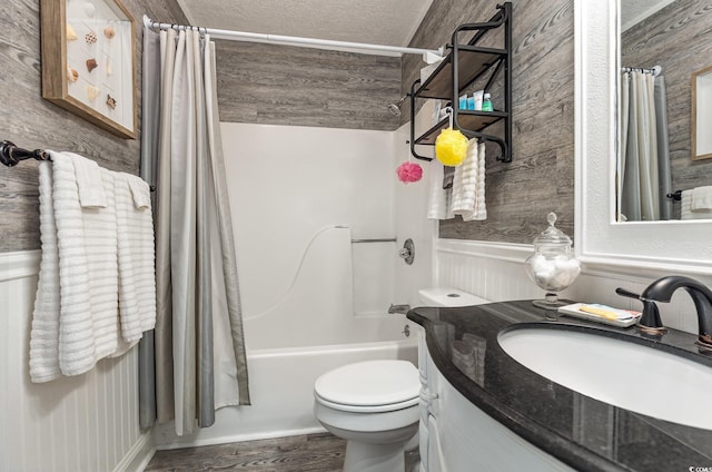 full bath with a textured ceiling, toilet, a wainscoted wall, vanity, and shower / bathtub combination with curtain