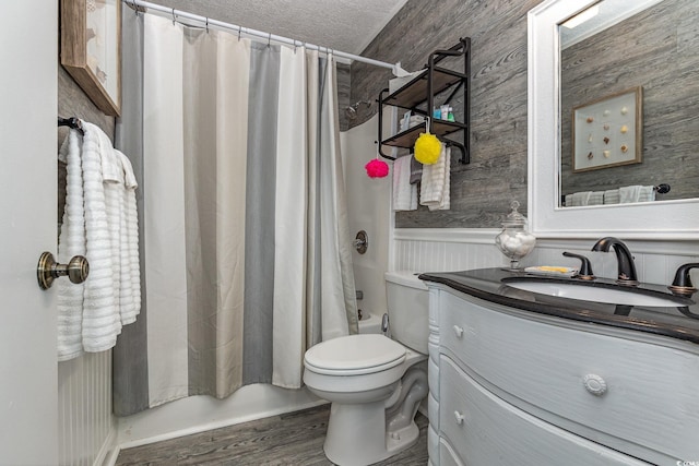 full bath with toilet, a wainscoted wall, wood finished floors, vanity, and shower / bath combo