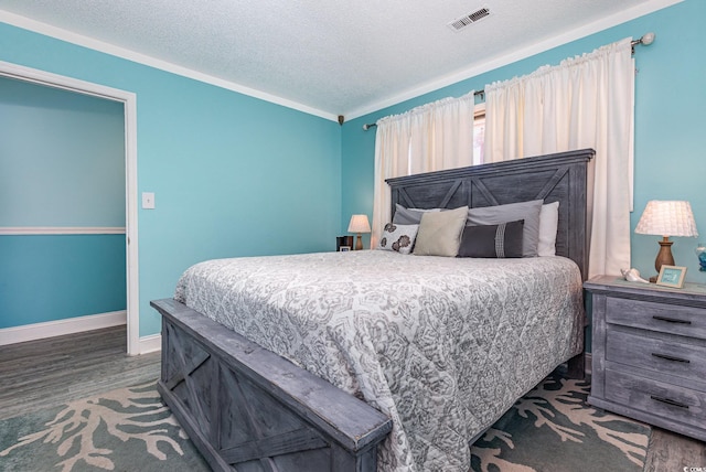 bedroom featuring a textured ceiling, wood finished floors, visible vents, and baseboards