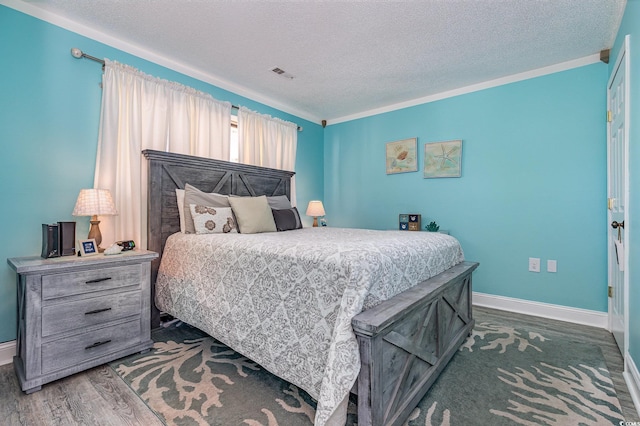 bedroom featuring baseboards, visible vents, wood finished floors, crown molding, and a textured ceiling