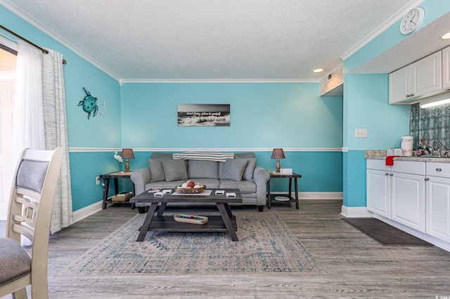 living area with crown molding, a textured ceiling, baseboards, and wood finished floors