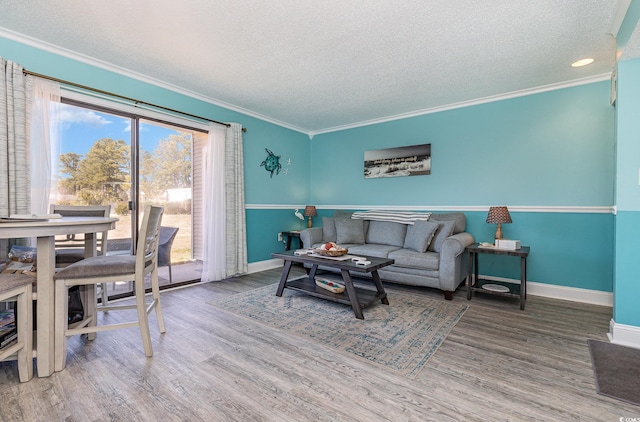 living area featuring a textured ceiling, ornamental molding, wood finished floors, and baseboards