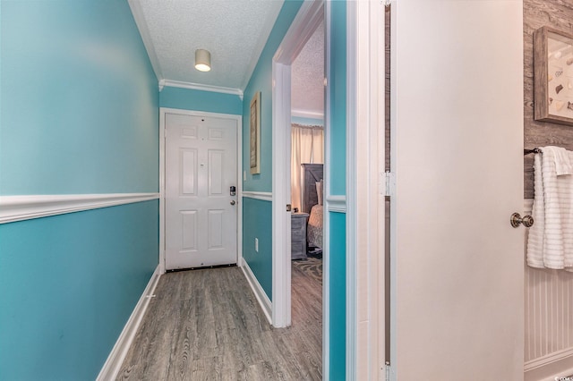 hallway featuring a textured ceiling, wood finished floors, and baseboards