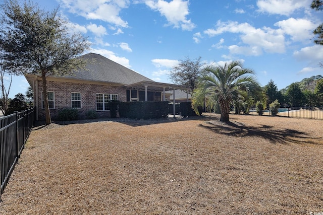 rear view of house with a fenced backyard, brick siding, and a pergola