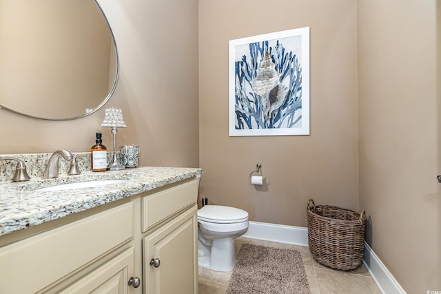 half bathroom with baseboards, vanity, toilet, and tile patterned floors