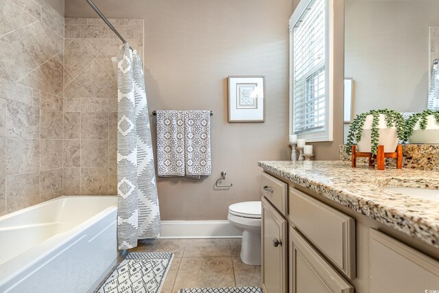 bathroom with toilet, vanity, baseboards, tile patterned floors, and shower / bath combo