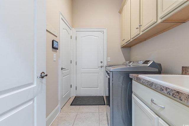 clothes washing area featuring light tile patterned floors, washing machine and clothes dryer, and cabinet space