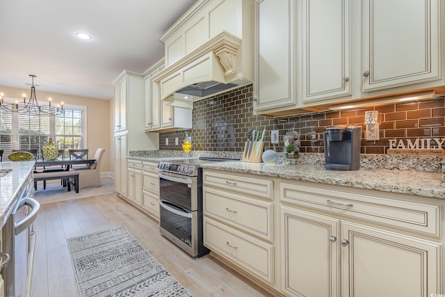 kitchen with cream cabinetry, backsplash, light wood-style floors, and double oven range