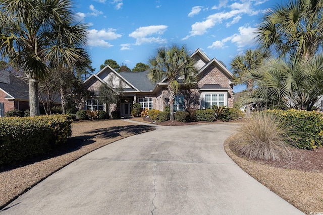 craftsman-style home with driveway and brick siding