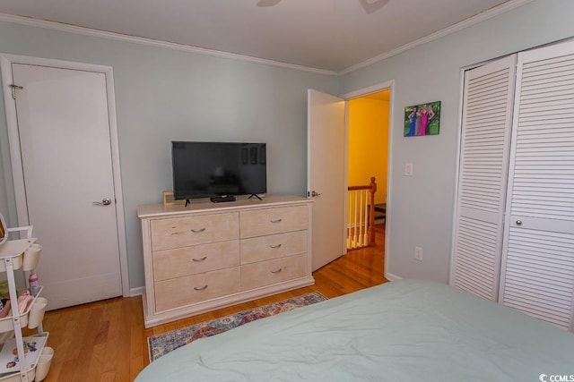 bedroom featuring a ceiling fan, a closet, light wood-style flooring, and crown molding
