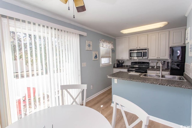 kitchen featuring a sink, light wood-style floors, freestanding refrigerator, electric range oven, and stainless steel microwave