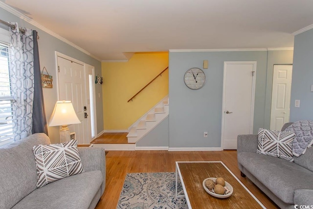living room featuring wood finished floors, crown molding, baseboards, and stairs