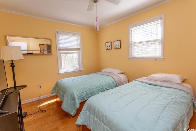bedroom featuring a ceiling fan, crown molding, baseboards, and wood finished floors