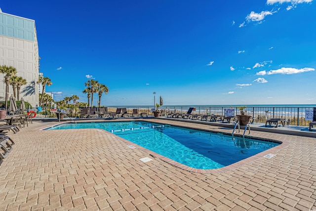 pool with a patio area and a water view