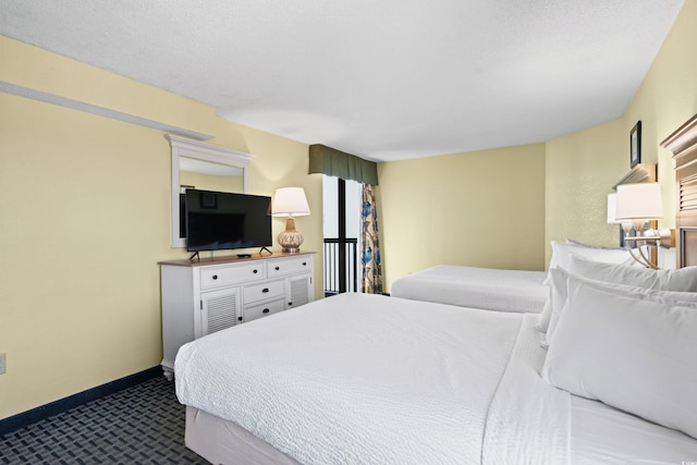 bedroom with a textured ceiling, dark carpet, and baseboards