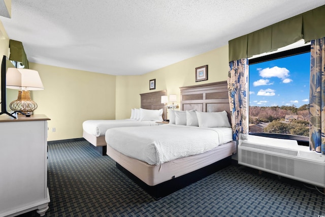 bedroom with baseboards, dark colored carpet, and a textured ceiling