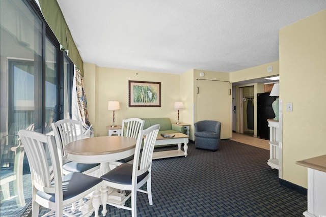 dining area featuring dark colored carpet, a textured ceiling, and baseboards