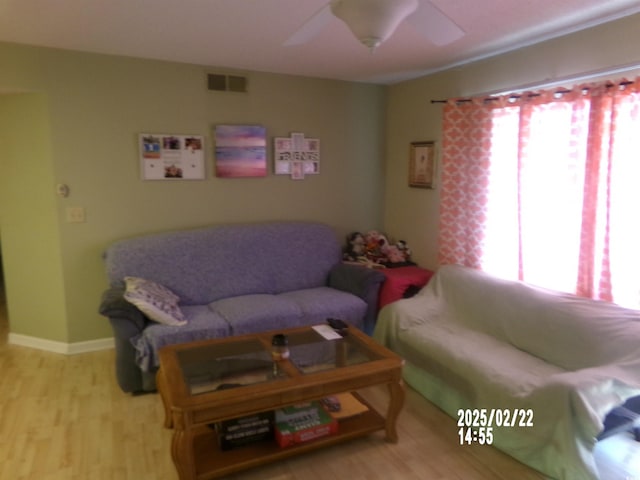 living area featuring baseboards, ceiling fan, visible vents, and wood finished floors