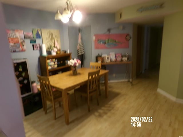 dining area with baseboards, wood finished floors, and an inviting chandelier