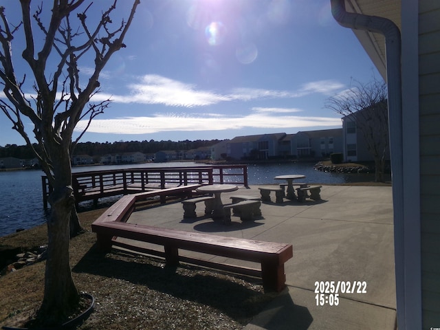 view of dock with a water view and a patio