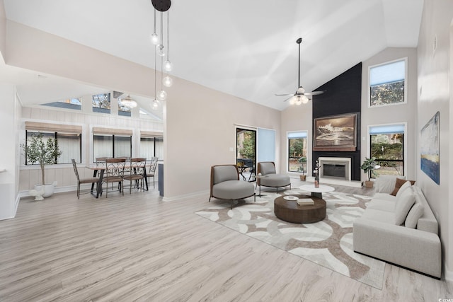 living room with high vaulted ceiling, a fireplace, wood finished floors, a ceiling fan, and baseboards