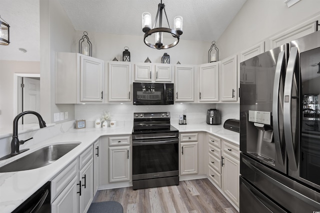 kitchen featuring decorative backsplash, black appliances, light wood-style flooring, and a sink