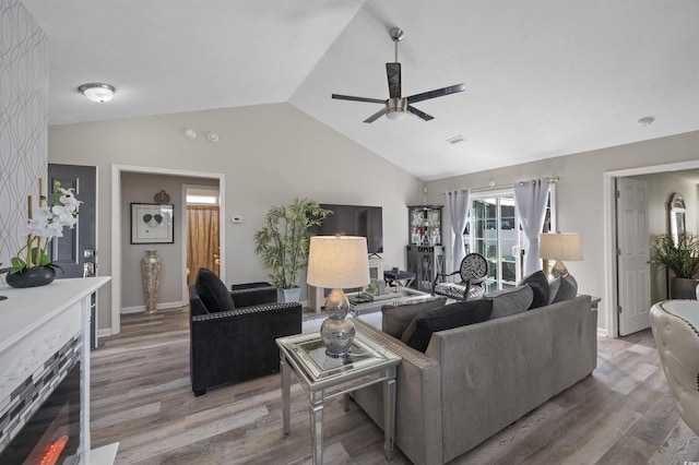 living area with visible vents, a ceiling fan, baseboards, light wood-style floors, and lofted ceiling