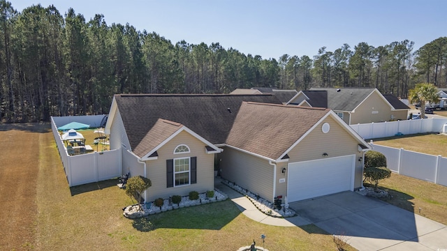 ranch-style home featuring a front lawn, driveway, an attached garage, and a fenced backyard