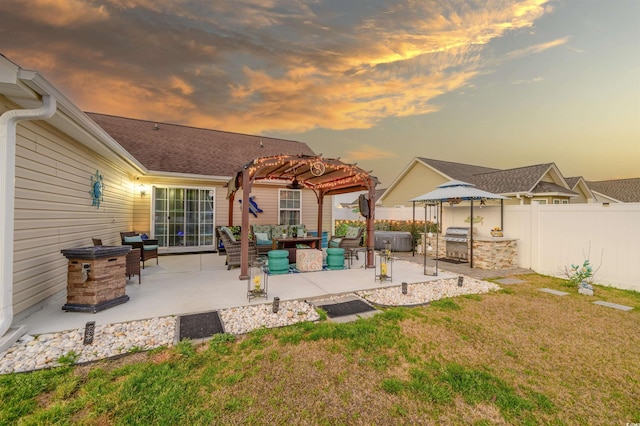 back of property featuring fence, a yard, an outdoor kitchen, a pergola, and a patio