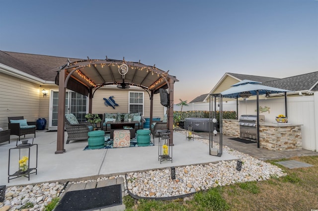 patio terrace at dusk with a pergola, an outdoor kitchen, outdoor lounge area, and fence