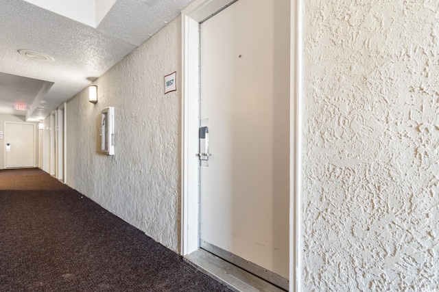 interior space featuring a textured ceiling, a textured wall, and carpet floors