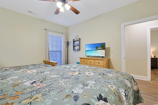 bedroom featuring a ceiling fan, visible vents, light wood-style flooring, and baseboards