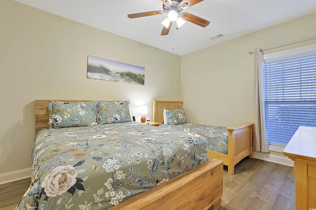 bedroom featuring baseboards, visible vents, ceiling fan, and wood finished floors