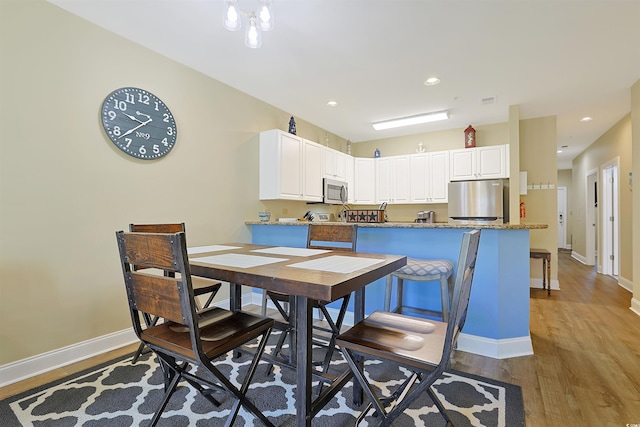 dining area featuring light wood finished floors, recessed lighting, and baseboards