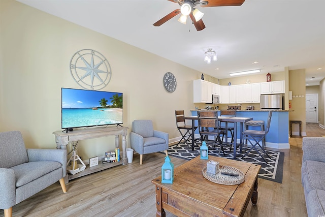 living room featuring a ceiling fan, light wood-style flooring, and baseboards