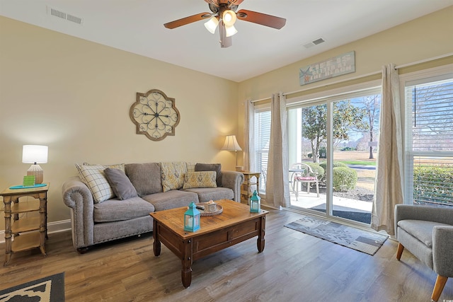 living area with a healthy amount of sunlight, visible vents, and wood finished floors