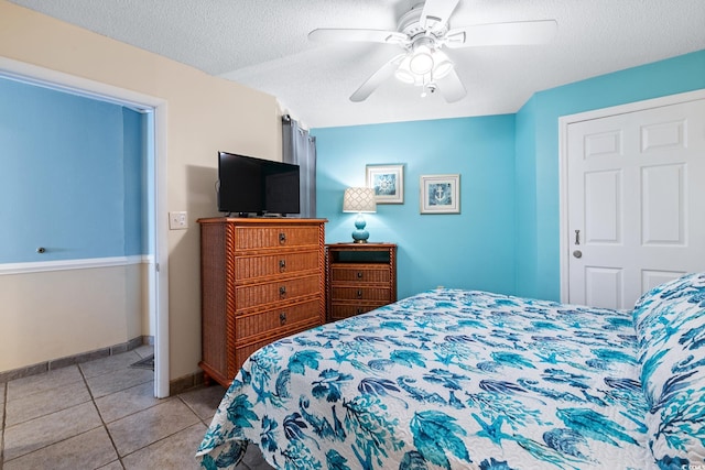 bedroom with a textured ceiling, ceiling fan, baseboards, and tile patterned floors