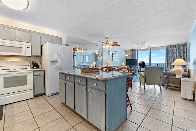 kitchen with a center island, gray cabinetry, open floor plan, a textured ceiling, and white appliances