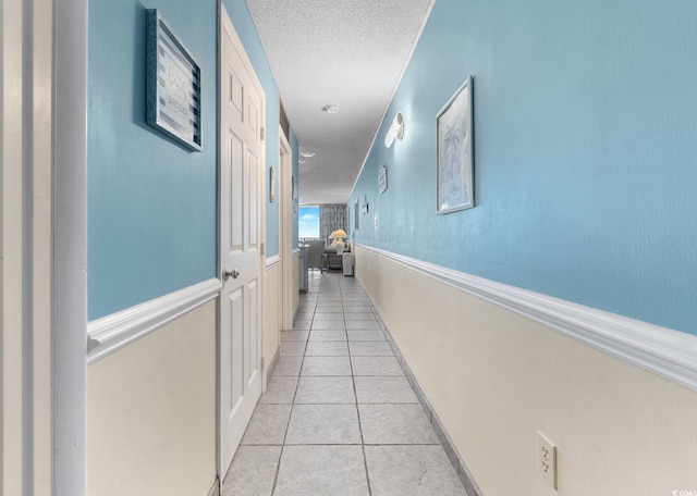 hallway featuring light tile patterned flooring and a textured ceiling